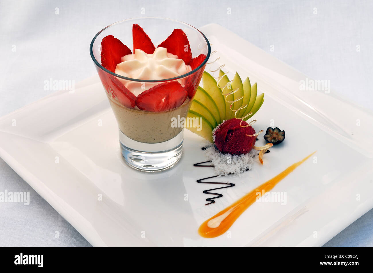 Il dessert, il Baileys mousse con sorbetto al lampone guarnito con fragole e fette di mela su una piastra bianca, Haute Cuisine Foto Stock