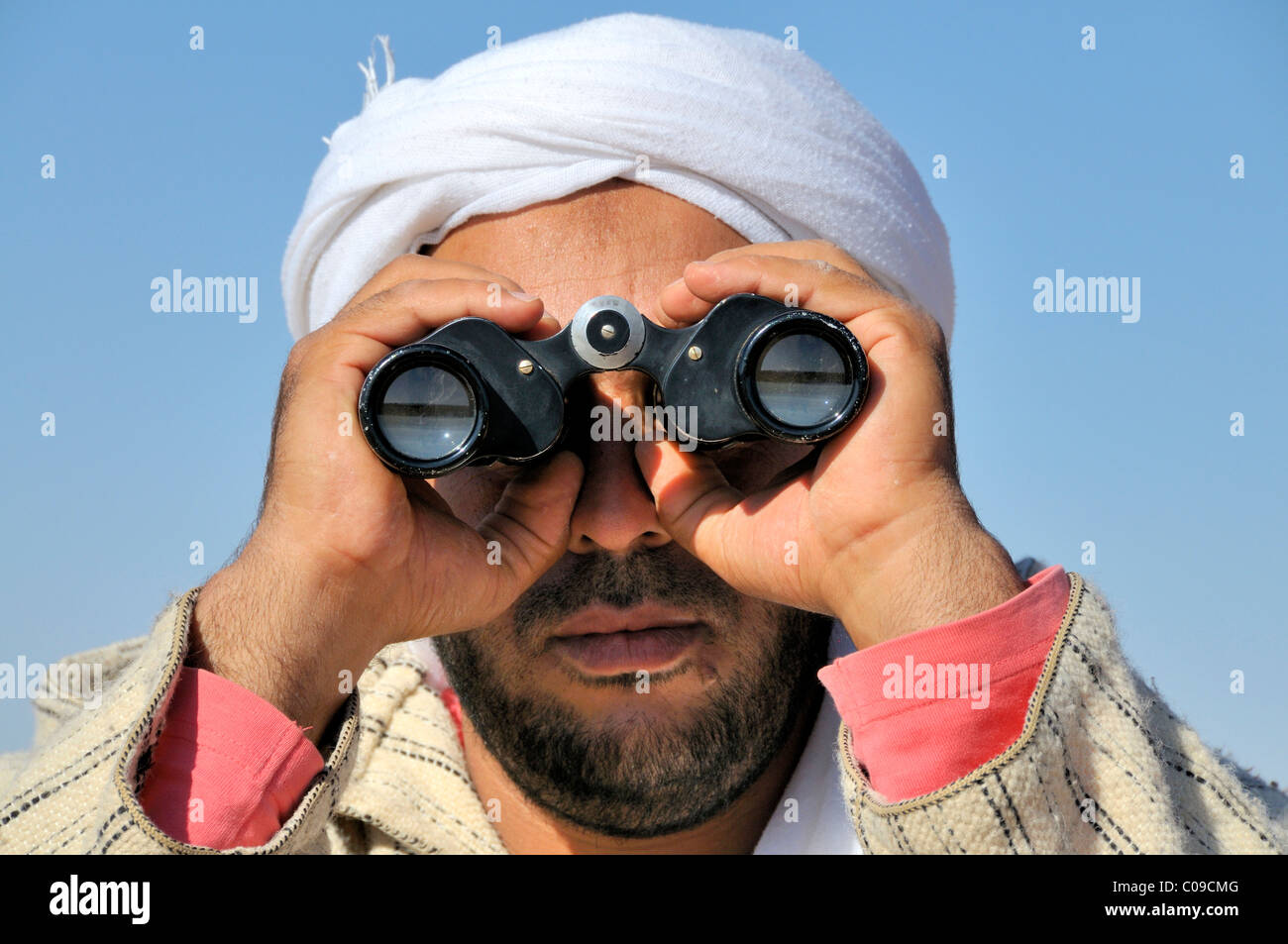 Berber con il tradizionale turbante Litham cercando animali persi con il binocolo, zona di confine tra il Marocco e l' Algeria Foto Stock