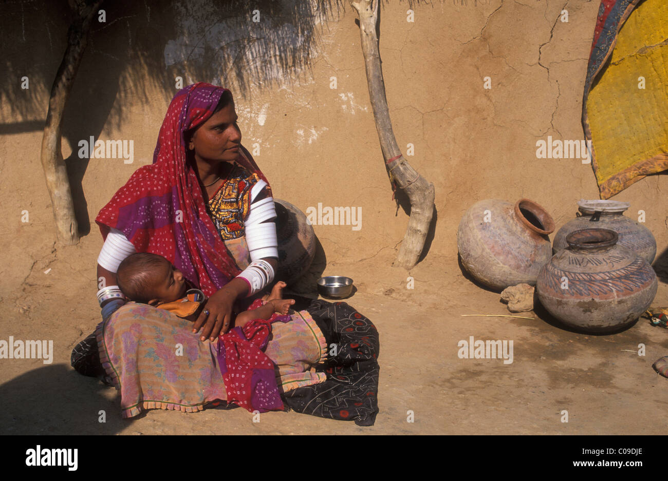 Donna che mantiene un bambino seduto di fronte a una casa, il Deserto di Thar, Rajasthan, India, Asia Foto Stock