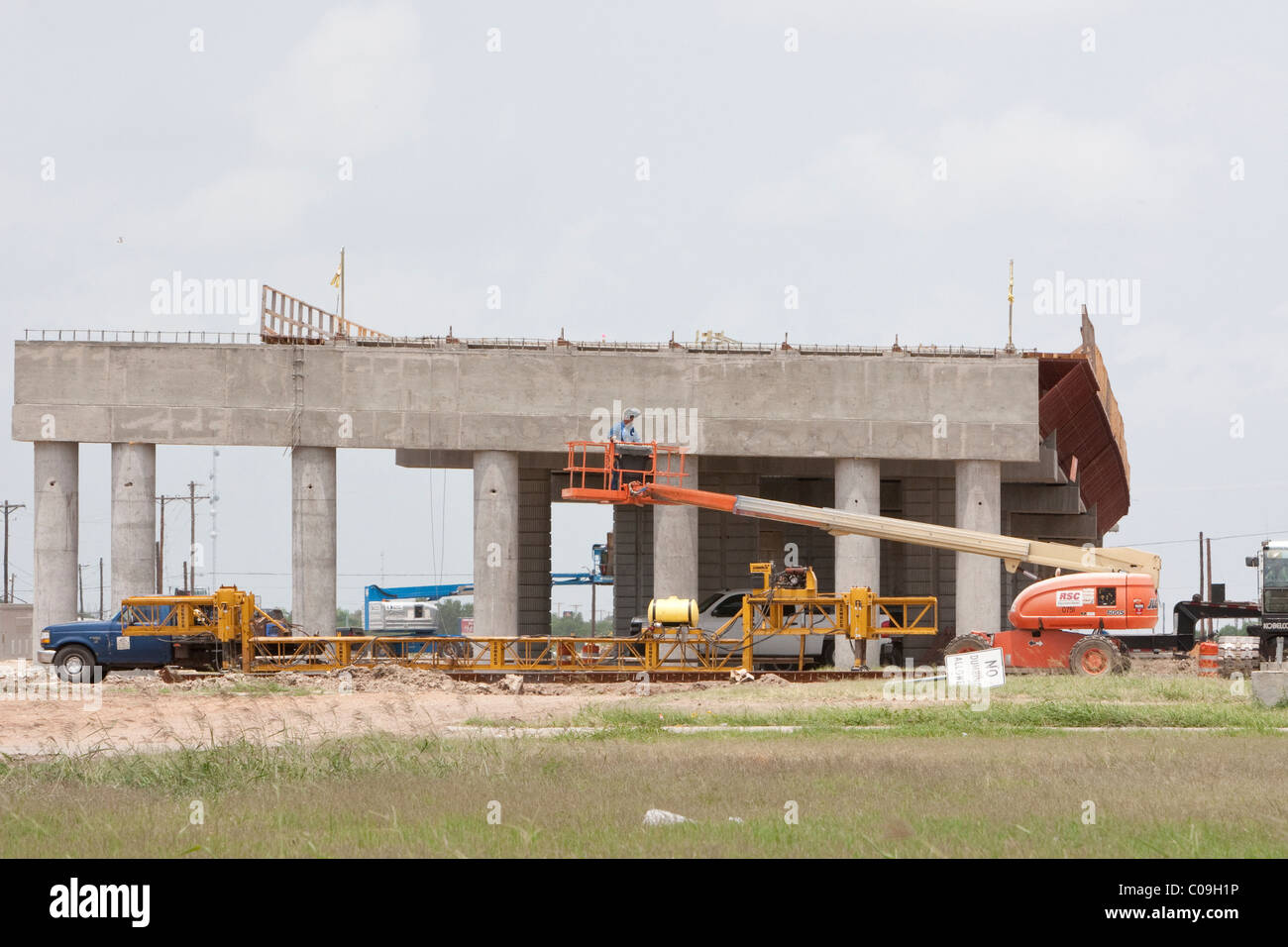 Hard-hat lavoratore sta nel carrello di sollevamento del braccio durante la costruzione del ponte sulla autostrada a Raymondville, Texas USA Foto Stock