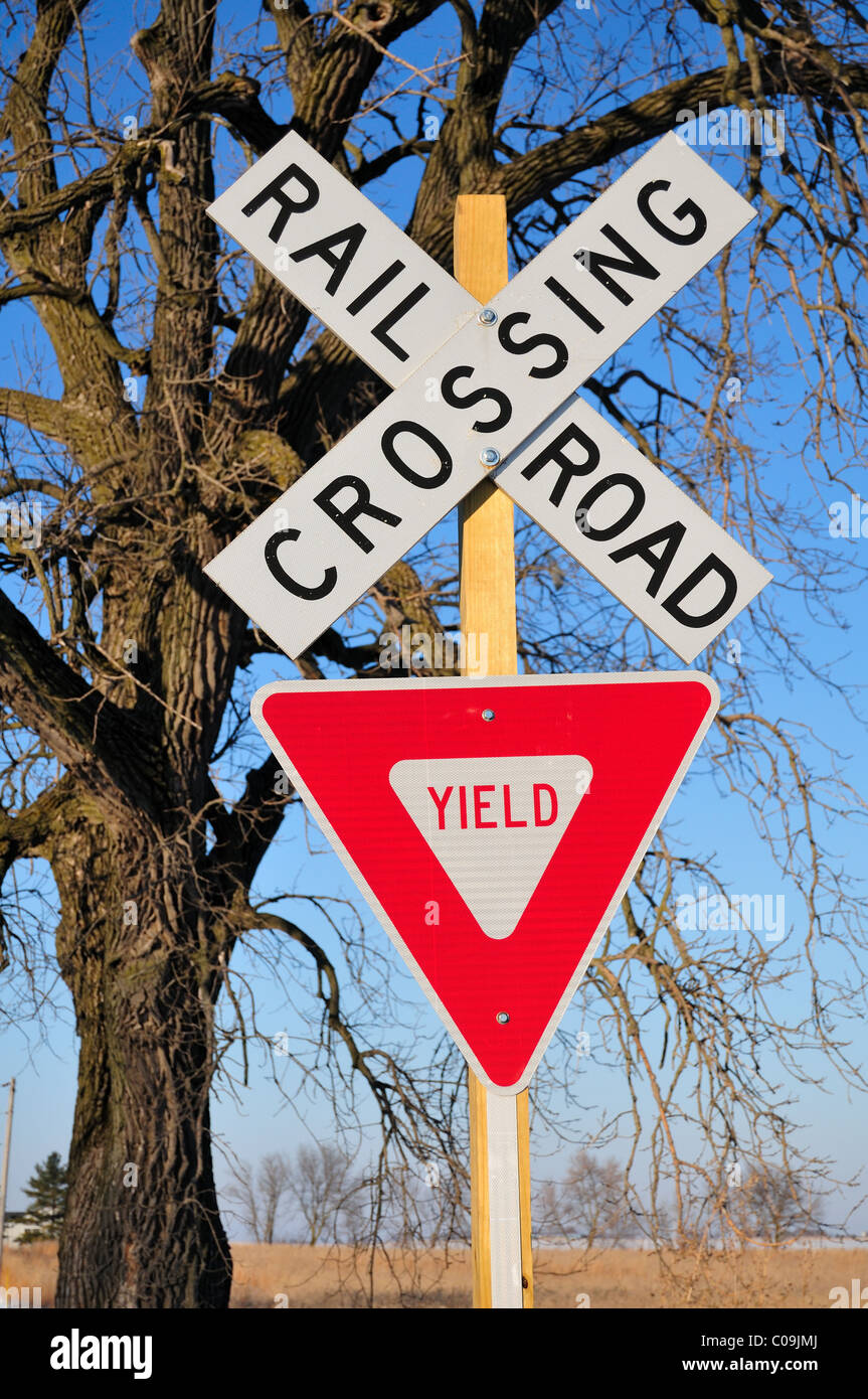 Un rurale attraversamento ferroviario segnati solo con cartelli stradali di sedersi di fronte a nodose vecchio albero in agricoltura paese in Illinois. Stati Uniti d'America. Foto Stock