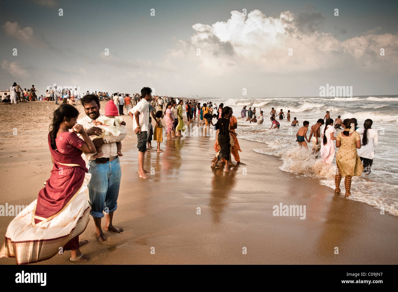 Migliaia di persone giocare nel surf a abeach durante il tramonto. Foto Stock