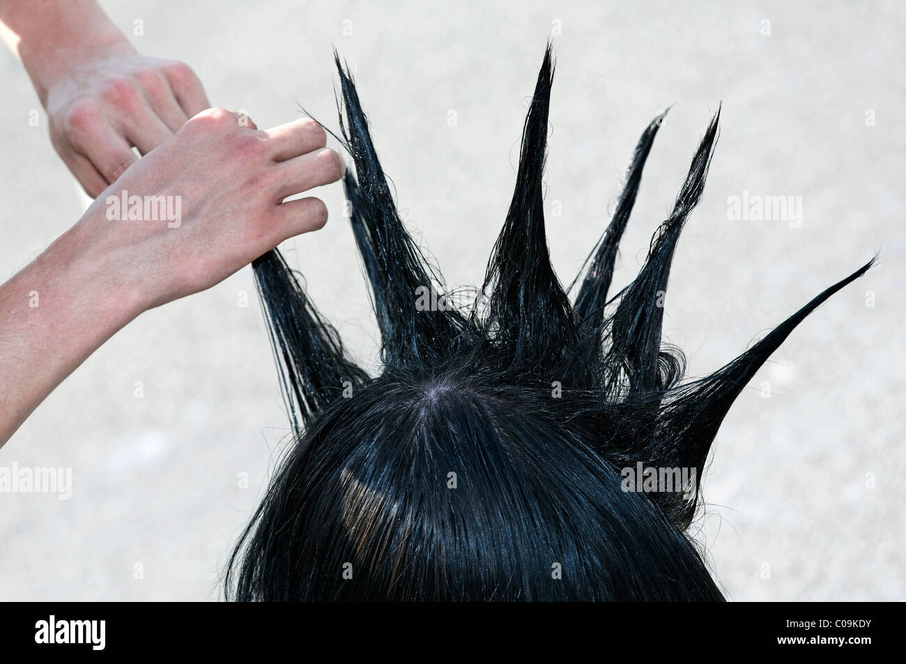 Le mani per lo styling dei capelli sagomata in suggerimenti di un adolescente, acconciatura con punte come una cresta di gallo, Mohawk, mohicano Foto Stock