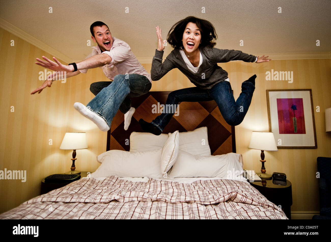 Ragazza e ragazzo saltando su un letto Foto Stock