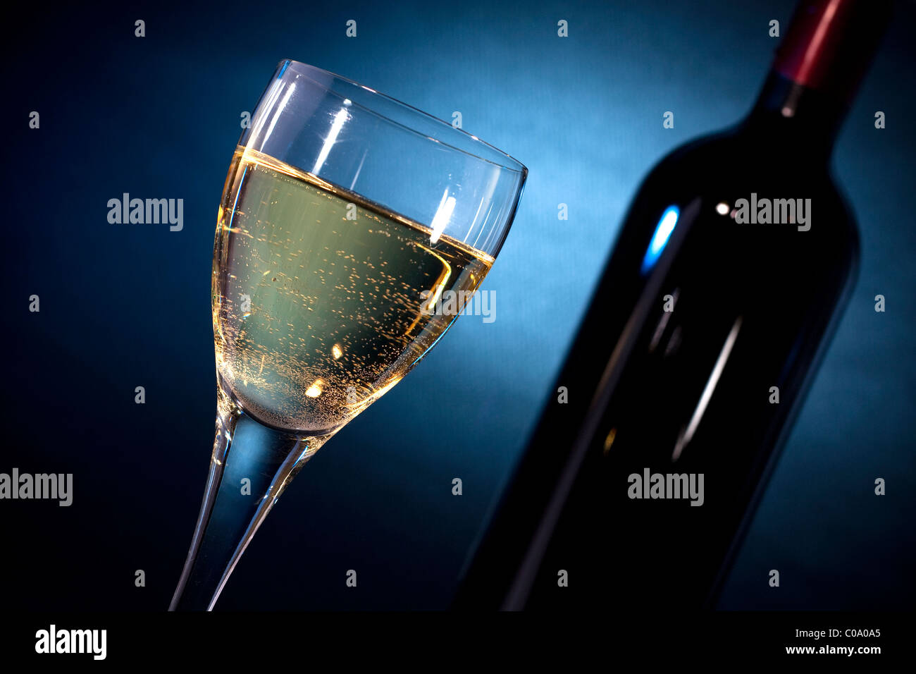 Vino bianco su di un vetro closeup & una bottiglia, sparare su sfondo nero con gel blu Foto Stock