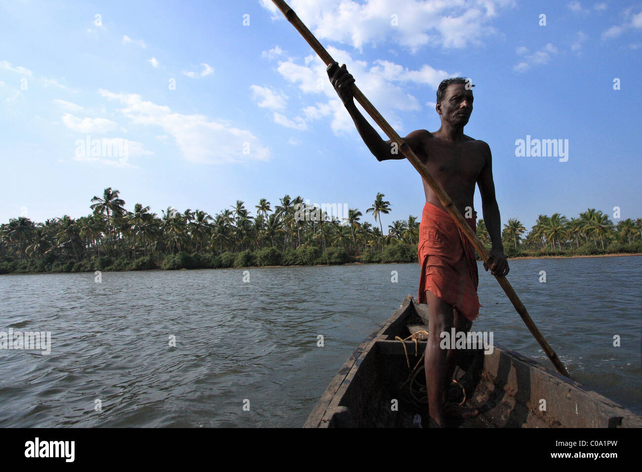 Villaggio locale uomo vela in una barca di legno nel retro acque del Kerala, India, Asia Foto Stock