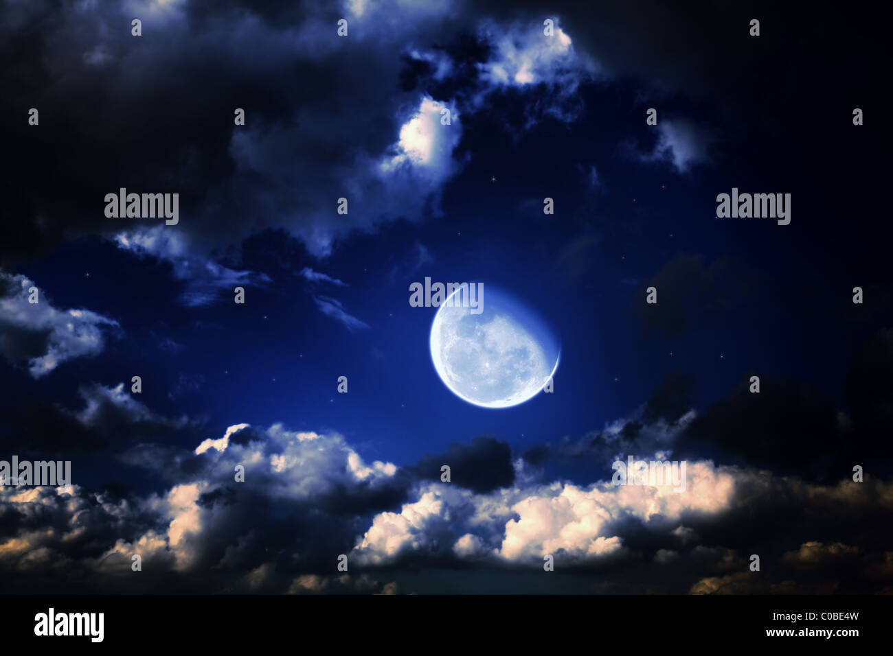 La luna e le stelle in un nuvoloso notte blu cielo Foto Stock