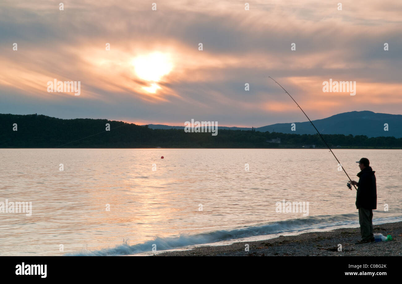 Il tramonto e il pescatore sulla spiaggia vicino a Oban Foto Stock
