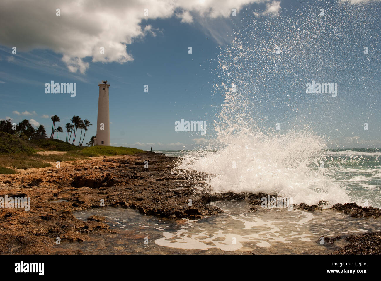 Grande onda a schiantarsi sulla costa rocciosa. Barbiere Point Lighthouse, Oahu Hawaii. Foto Stock