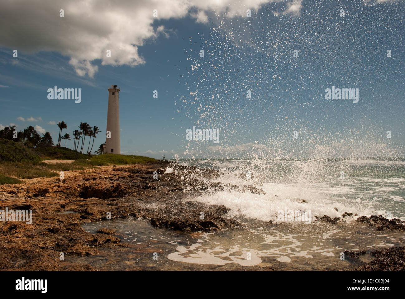 Grande onda a schiantarsi sulla costa rocciosa. Barbiere Point Lighthouse, Oahu Hawaii. Foto Stock