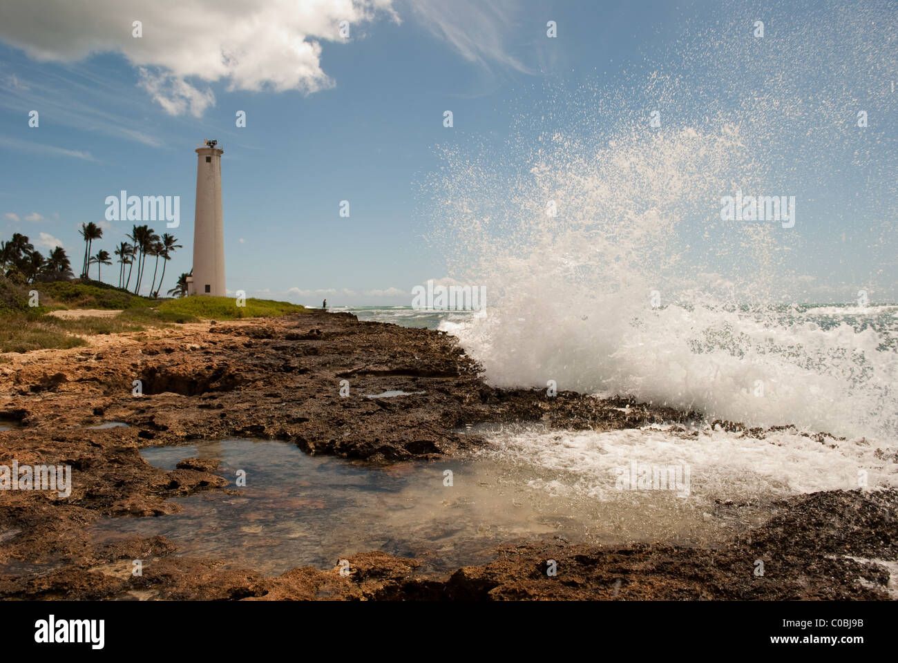 Grande onda a schiantarsi sulla costa rocciosa. Barbiere Point Lighthouse, Oahu Hawaii. Foto Stock