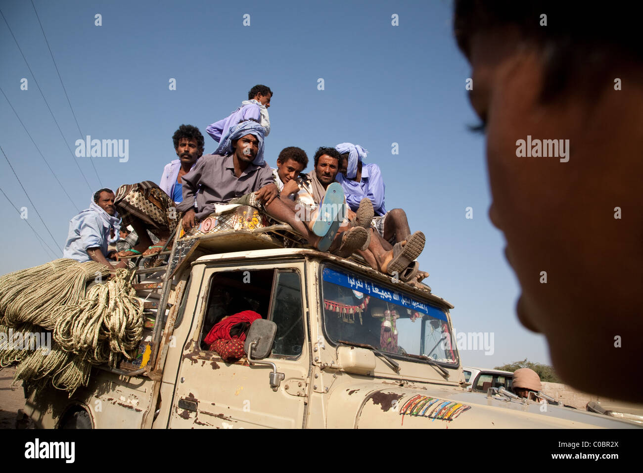 La gente arriva su un tetto di un piccolo camion presso il mercato del venerdì a Beit al-Faqih, Yemen Foto Stock