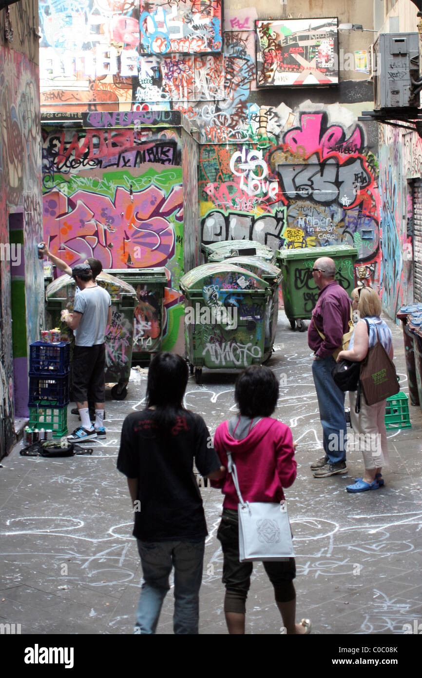 Curiosi guarda come taggers parete a spruzzo con graffiti, Melbourne, Nuovo Galles del Sud, Australia Foto Stock