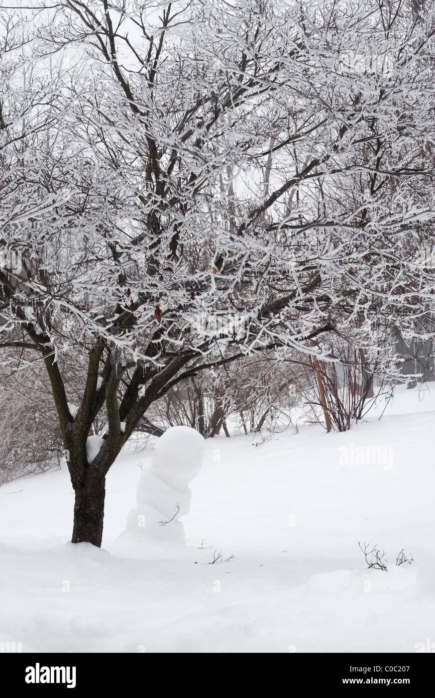 Pupazzo di neve sotto un albero di inverno Foto Stock