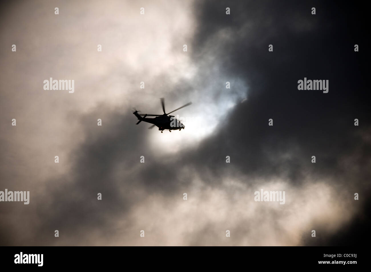 Una guardia costiera elicottero con rotori sfocata battenti nel buco nero nelle nubi alterando la tempesta finanziaria, Foto Stock