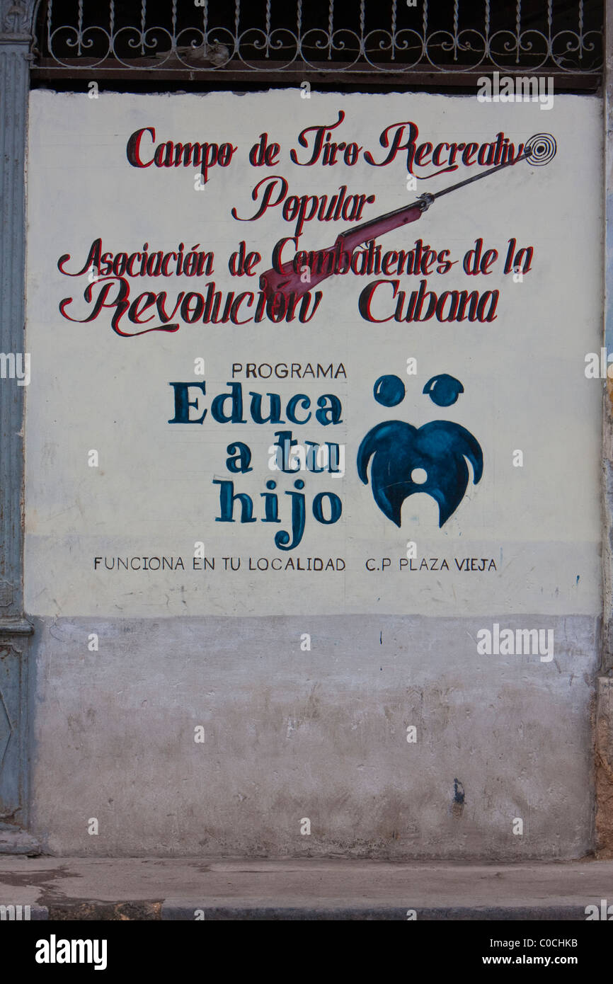 Cuba, La Habana. Poster di incoraggiare i padri ad insegnare ai loro figli ricreative pratica di armi da fuoco. Foto Stock