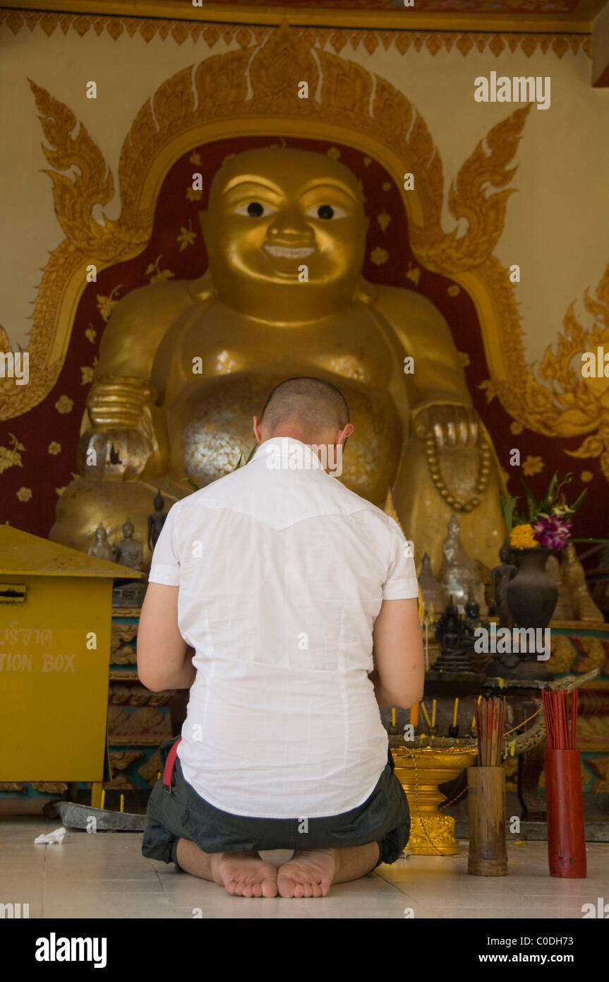 Thailandia, Ko Samui (aka Koh Samui). Tempio di Big Buddha sulla ventola isola. Uomo che prega davanti la statua di Buddha. Foto Stock