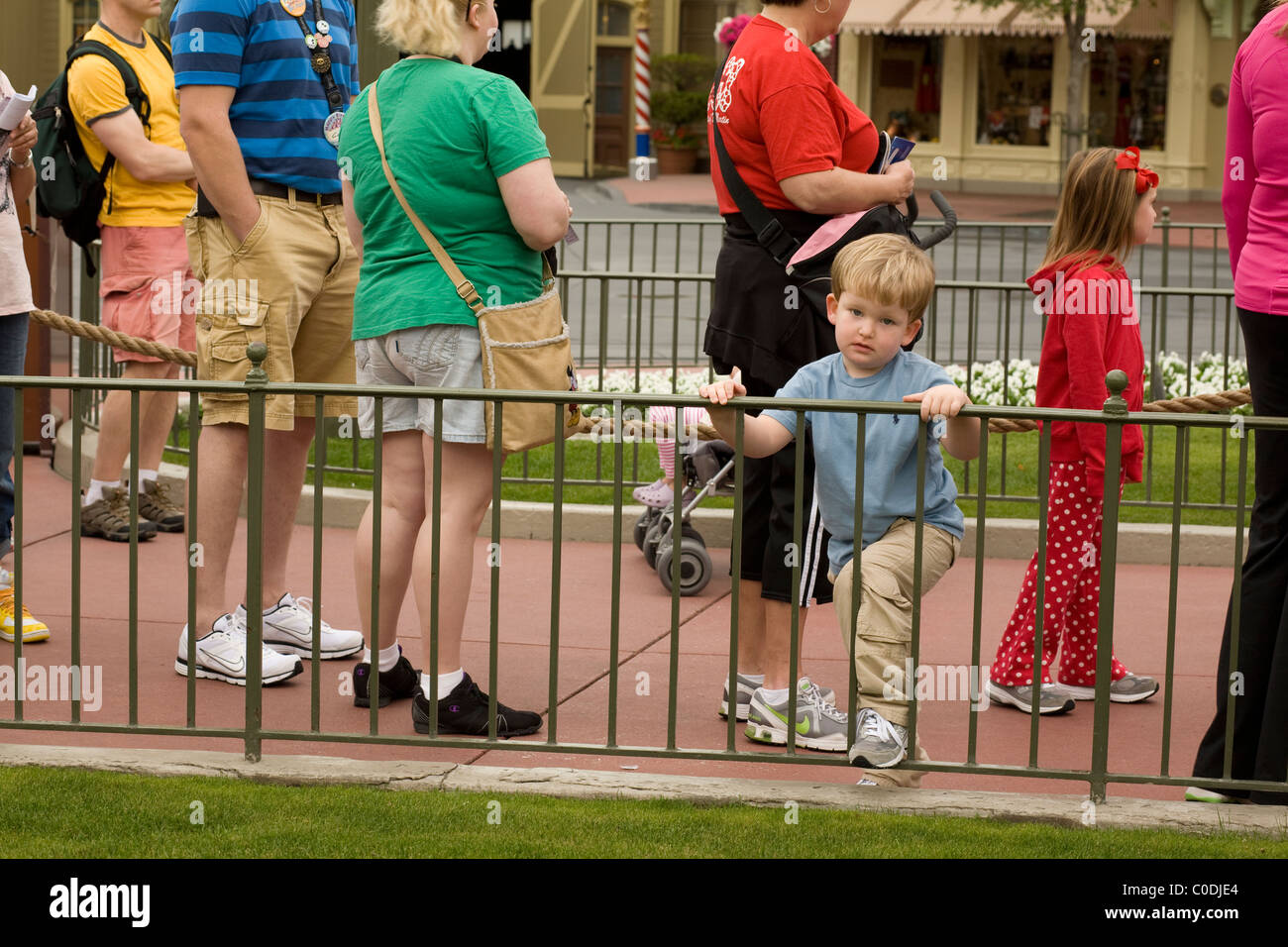 Un ragazzo annoiato attende con altri per avere il suo ritratto preso con un personaggio Disney a Disney World Magic Kingdom di Orlando. Foto Stock