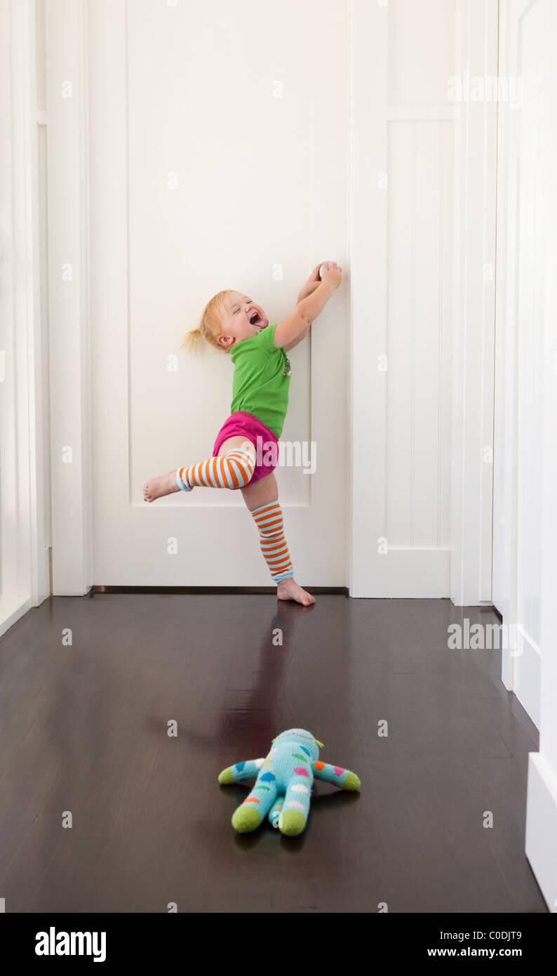 Bambina cercando di arrivare a porta chiusa Foto Stock
