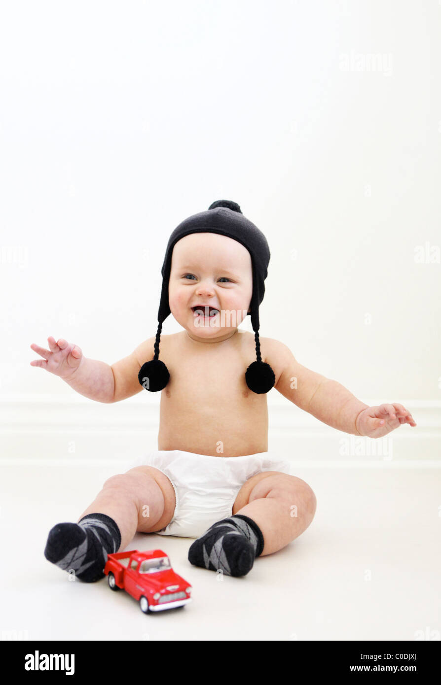 Baby boy nel pannolino e winter hat giocando con un carrello Foto Stock