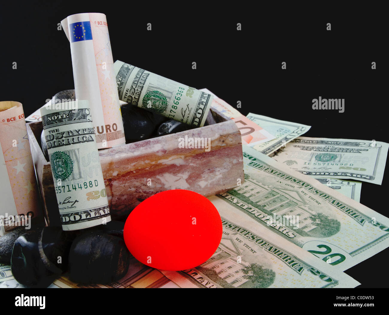 Casella di marmo con euro e dollaro valuta e un nido arrossate uovo su rocce raffigurano turbato i mercati e le pensioni. Foto Stock