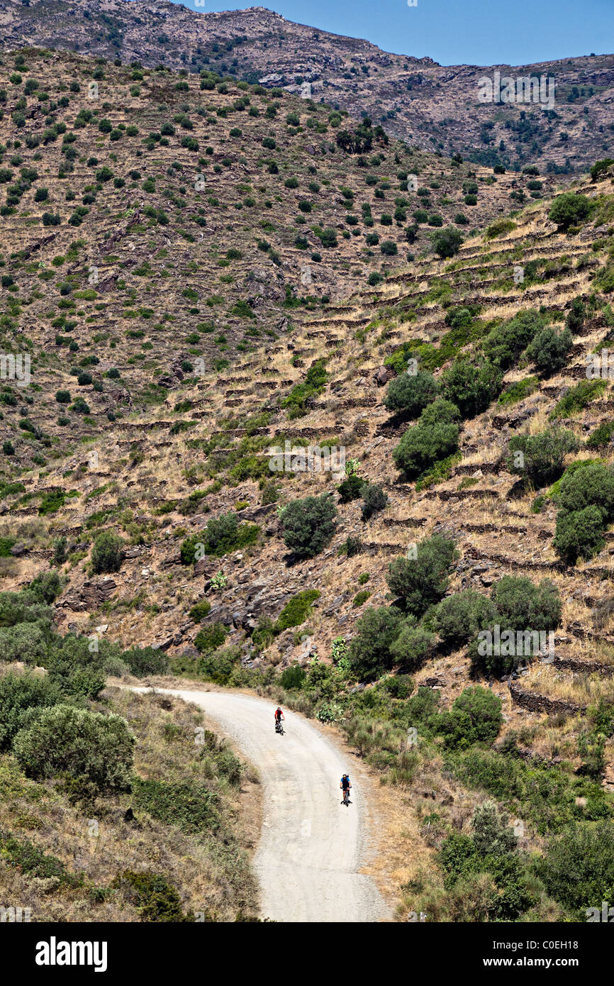 Due ciclisti su strada sterrata attraverso montagne Parc Natural de Cap de Creus Emporda Catalunya Spagna Foto Stock