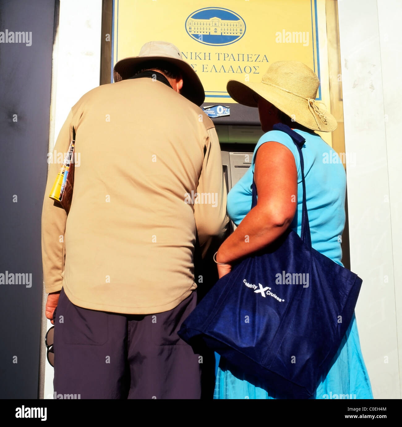 Una coppia di turisti senza volto di mezza età che riceve denaro da un bancomat di Santorini, isole greche, Grecia KATHY DEWITT Foto Stock