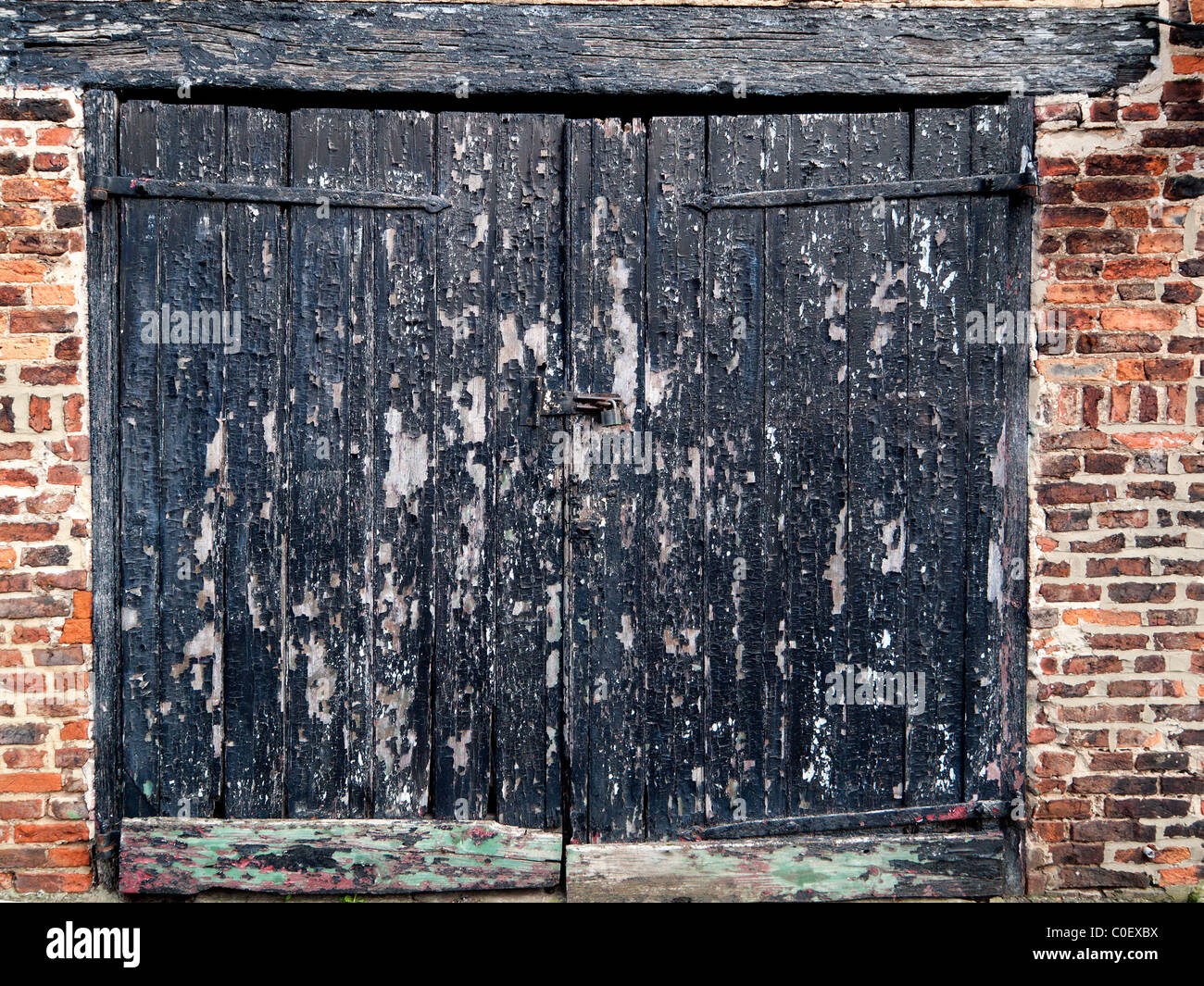 Vecchio garage in legno porta in necessità di ristrutturazione con vernice nera la pelatura Foto Stock