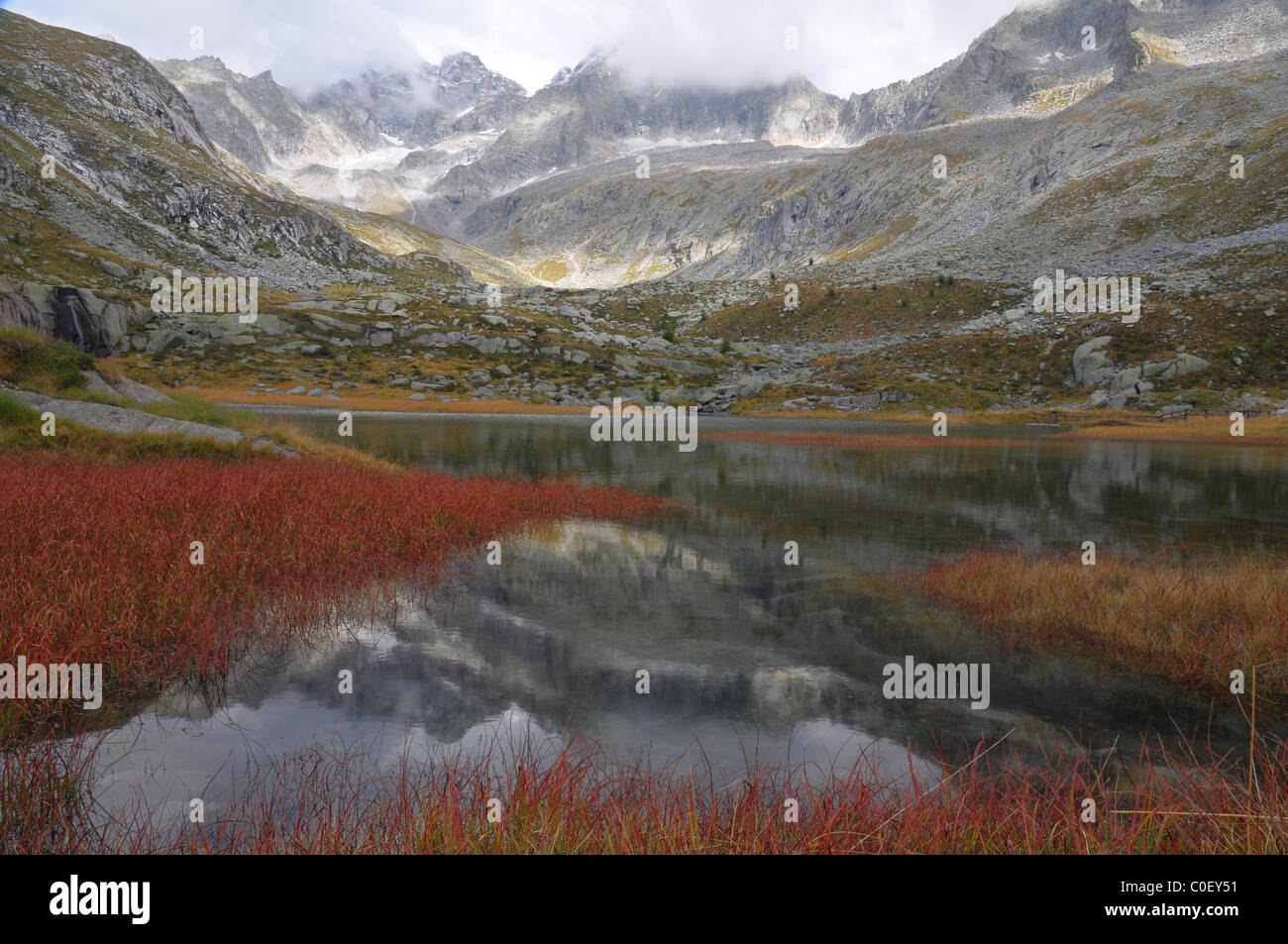 HDR elevata paesaggio di montagna con tarn (lago), lamelle di rosso o di erbe e di un circo glaciale (combe) Foto Stock