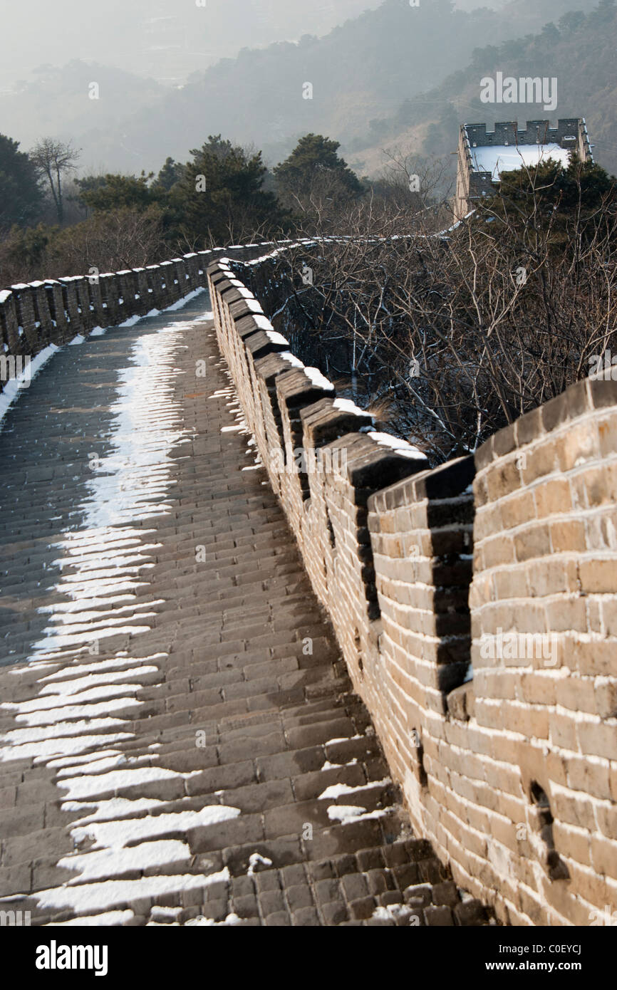 La neve su alcuni ripidi e passaggi irregolare portando ad una dinastia Ming torre di avvistamento sulla Mutianyu tratto della Grande Muraglia Cinese. Foto Stock