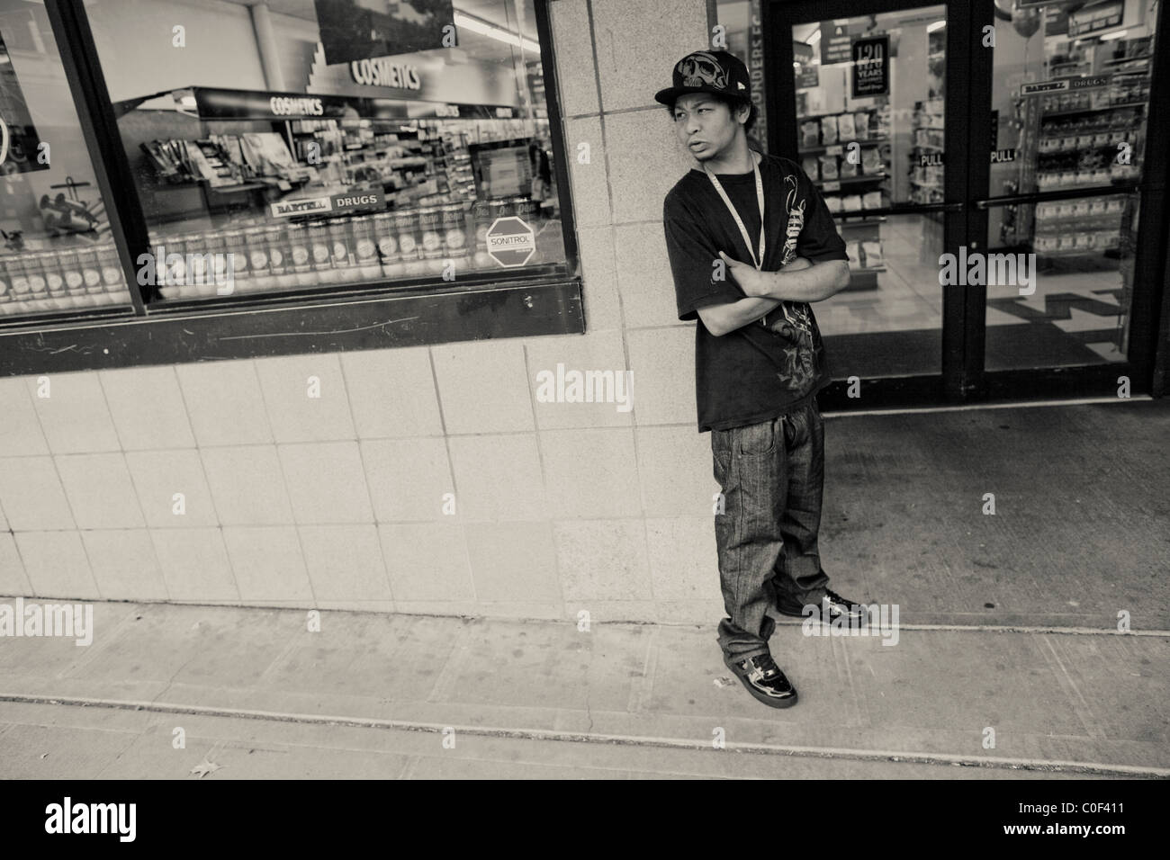 Un giovane senzatetto aspetta un amico di fronte a una farmacia nel quartiere universitario di Seattle Foto Stock