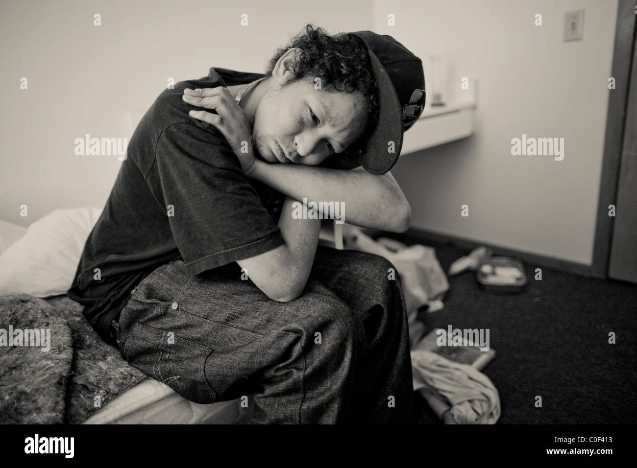 Un senzatetto giovane adulto si siede nella sua stanza a una temporanea struttura di alloggiamento per i senzatetto il 3 ottobre 2010 Foto Stock