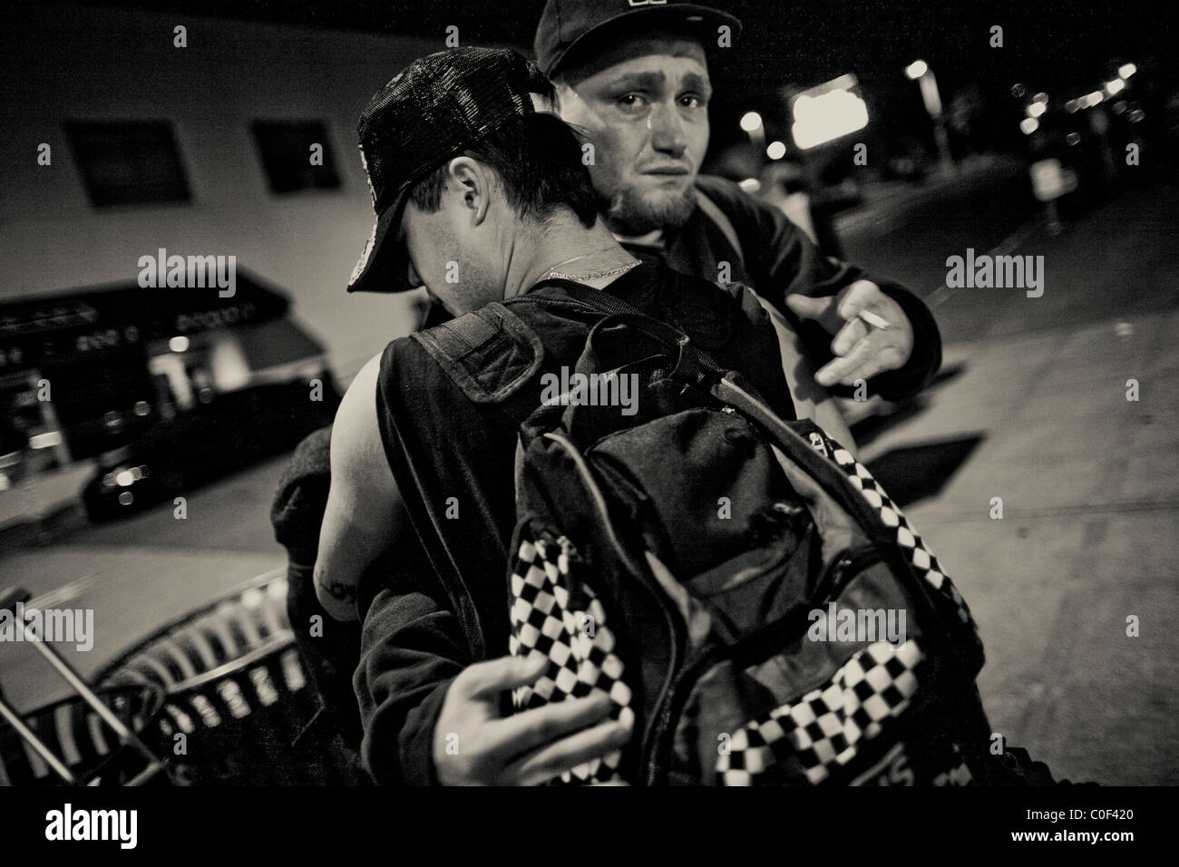 Un giovane senzatetto abbraccia un amico mentre dice addio alla sua ultima notte in città nel quartiere universitario di Seattle Foto Stock