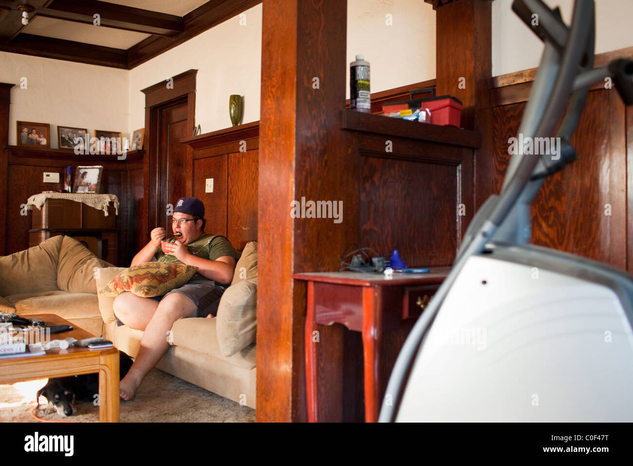 La Grange, California, Stati Uniti. American Teen mangia la sua colazione sul divano mentre si guarda la TV. Foto Stock