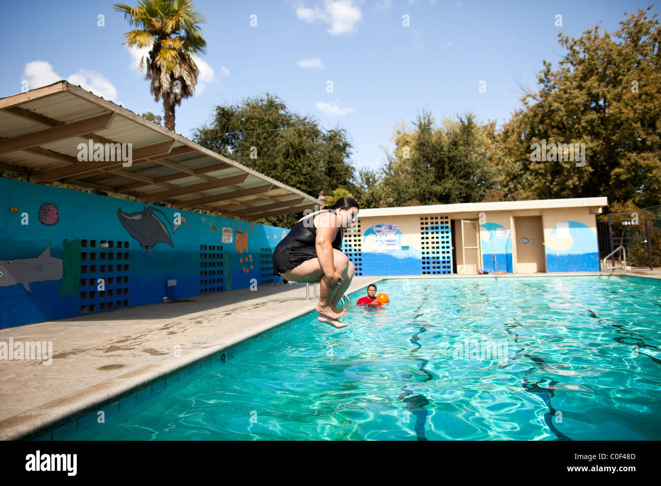 Reedley, California, Stati Uniti. Un obeso ragazza adolescente fa una palla di cannone in una piscina. Foto Stock
