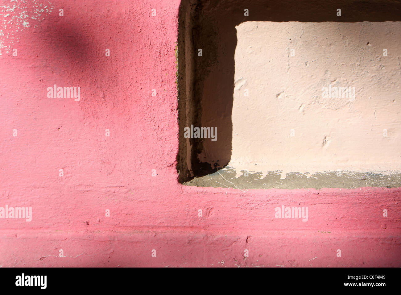 Parete rosa con macchie di luce dal sole Foto Stock
