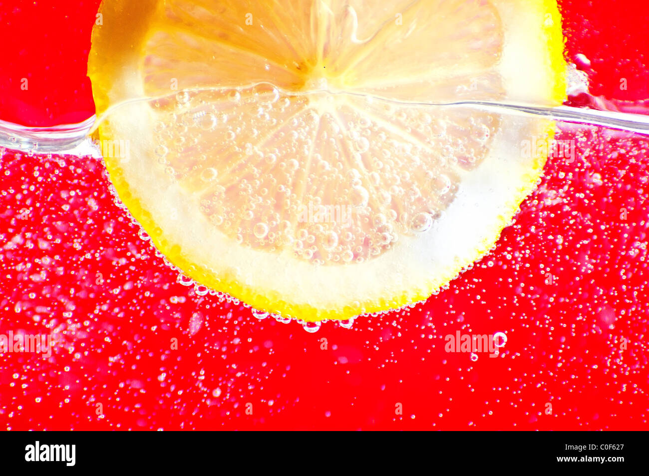 Close-up di una fetta di limone con bolle su rosso Foto Stock