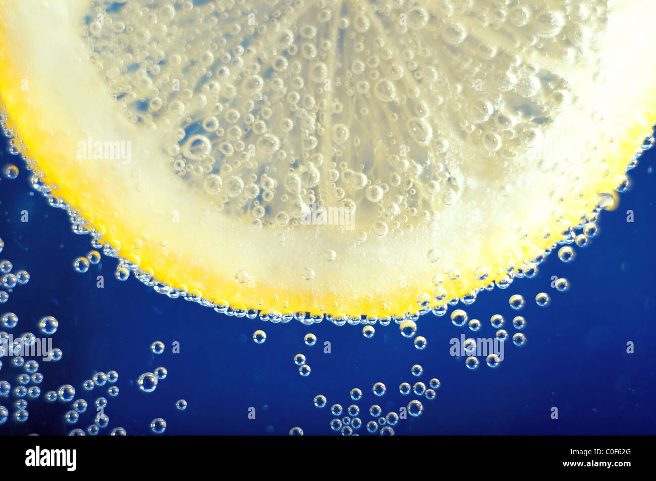 Close-up di una fetta di limone con bolle su blu Foto Stock