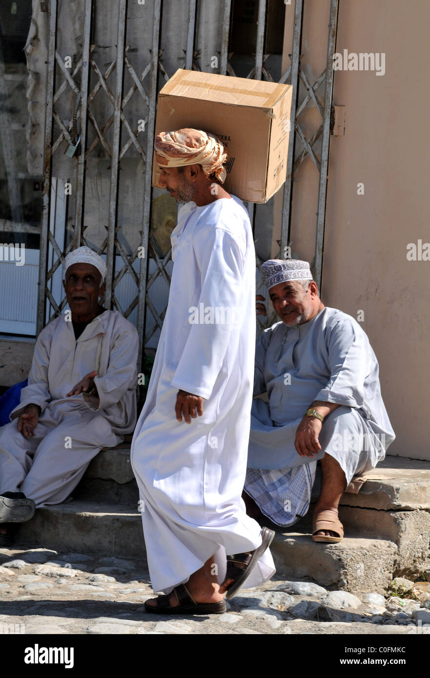 Il Sultanato di Oman. street scene, uomo scatola di trasporto Foto Stock