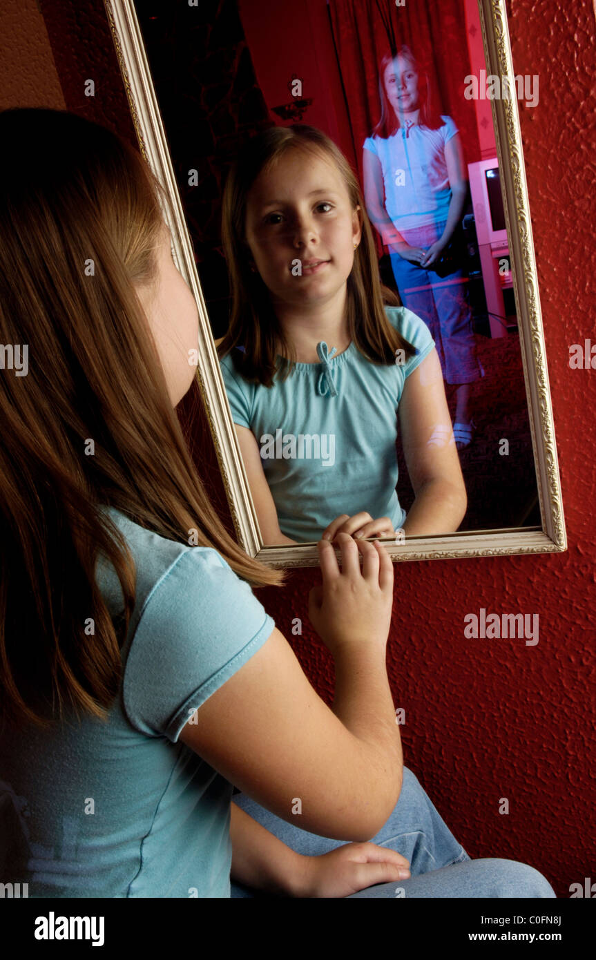 Una giovane ragazza guardando in uno specchio e vedere un fantasma del suo  letti in camera dietro di lei Foto stock - Alamy