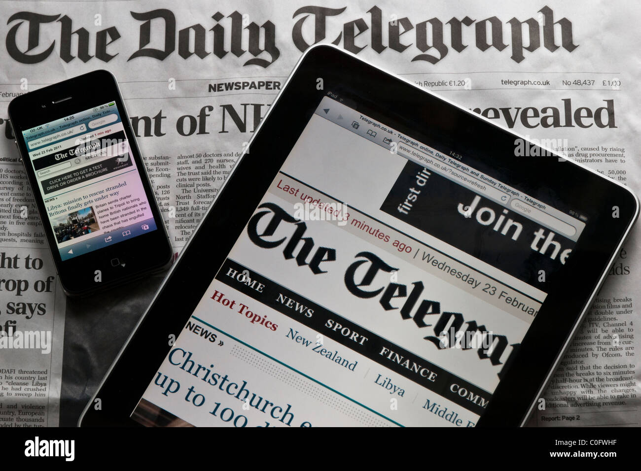 Un Apple iPad e Apple iPhone sedersi sulla parte superiore della versione stampata del Daily Telegraph. Un esempio di New Media Vs Old Media. Foto Stock
