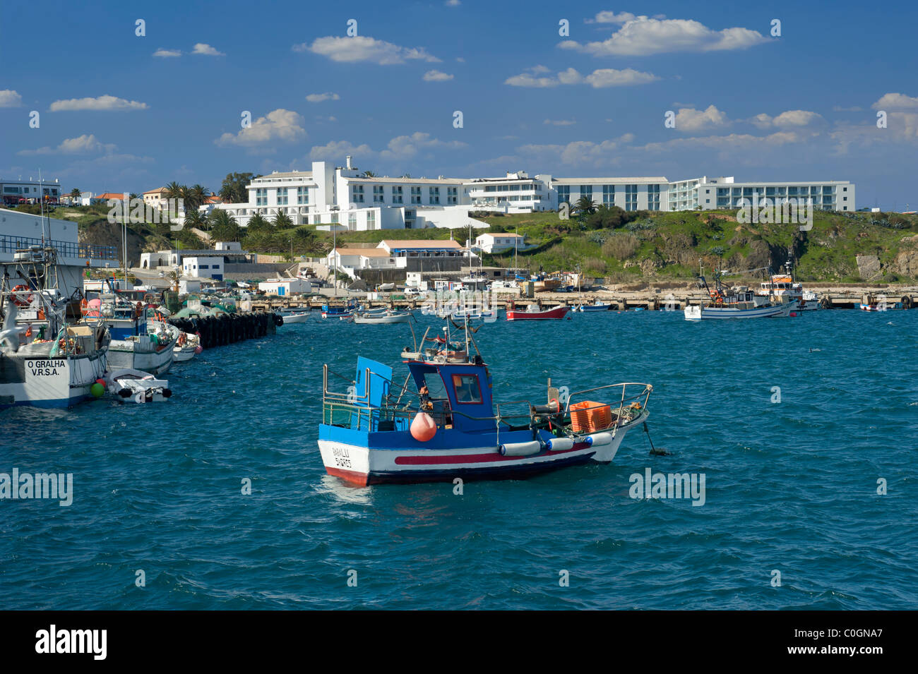 Il Portogallo, Algarve, Sagres, una barca da pesca nel porto con la Memmo Baleeira Hotel sulla scogliera Foto Stock