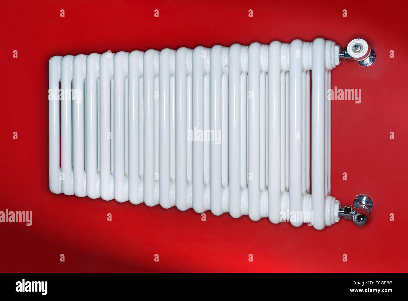 Bianco radiatore di riscaldamento su un muro rosso Foto Stock