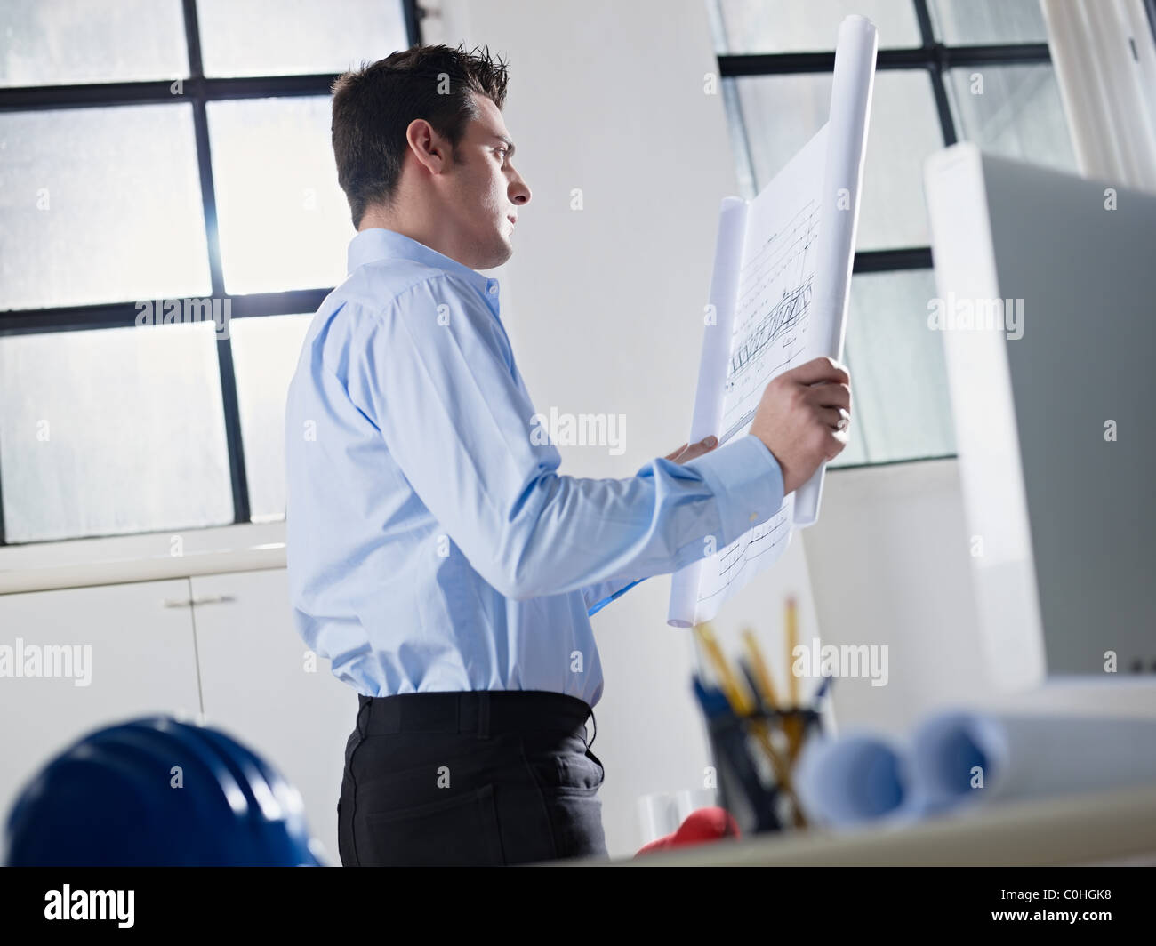 La metà degli adulti maschi caucasici architetto esame piano di costruzione. Sagoma orizzontale, vita, vista laterale Foto Stock