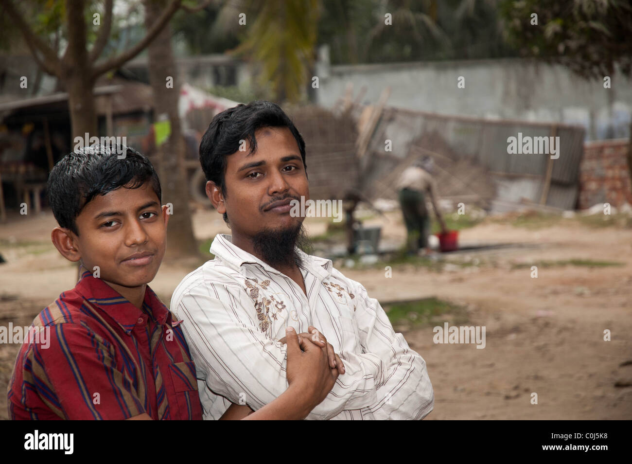 Un ritratto di due giovani uomini del Bangladesh, in corrispondenza di un bordo strada garage sulle Chittagong autostrada Foto Stock