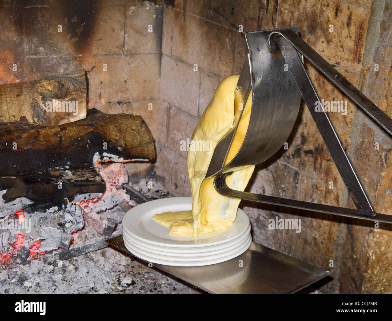 Ruota di formaggio raclette la fusione prima del camino Foto Stock