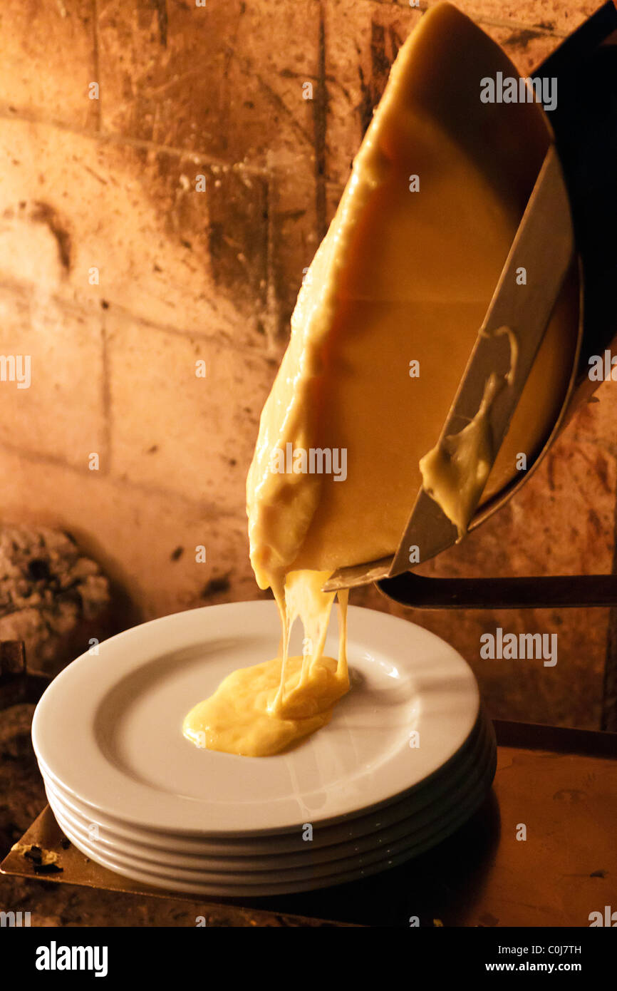 Ruota di formaggio raclette la fusione prima del camino Foto Stock