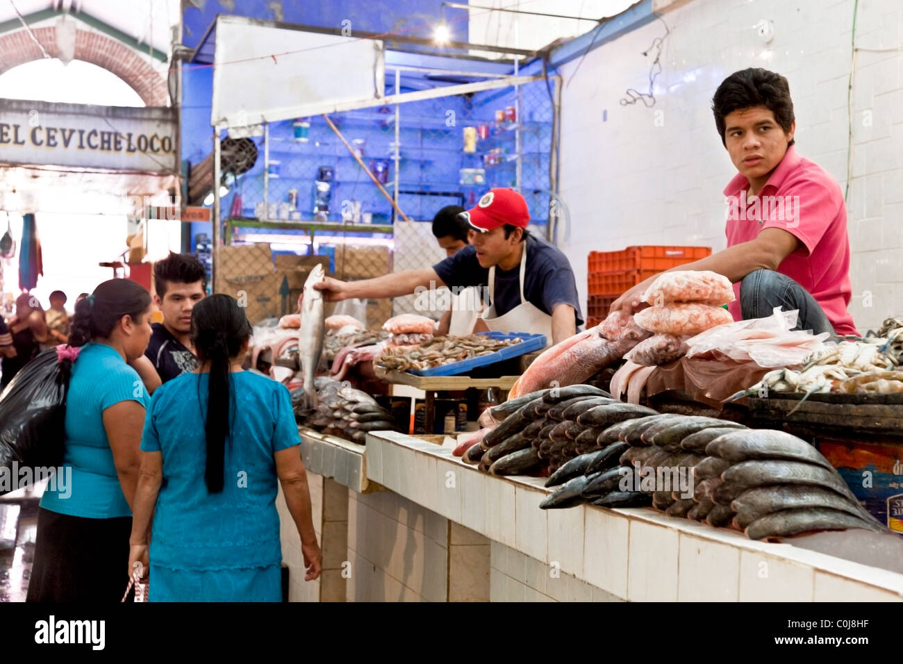 Occupato il contatore di pesce a Benito Juarez di mercato con countermen clienti & pile di pesce intero esposti per la vendita Oaxaca Messico Foto Stock