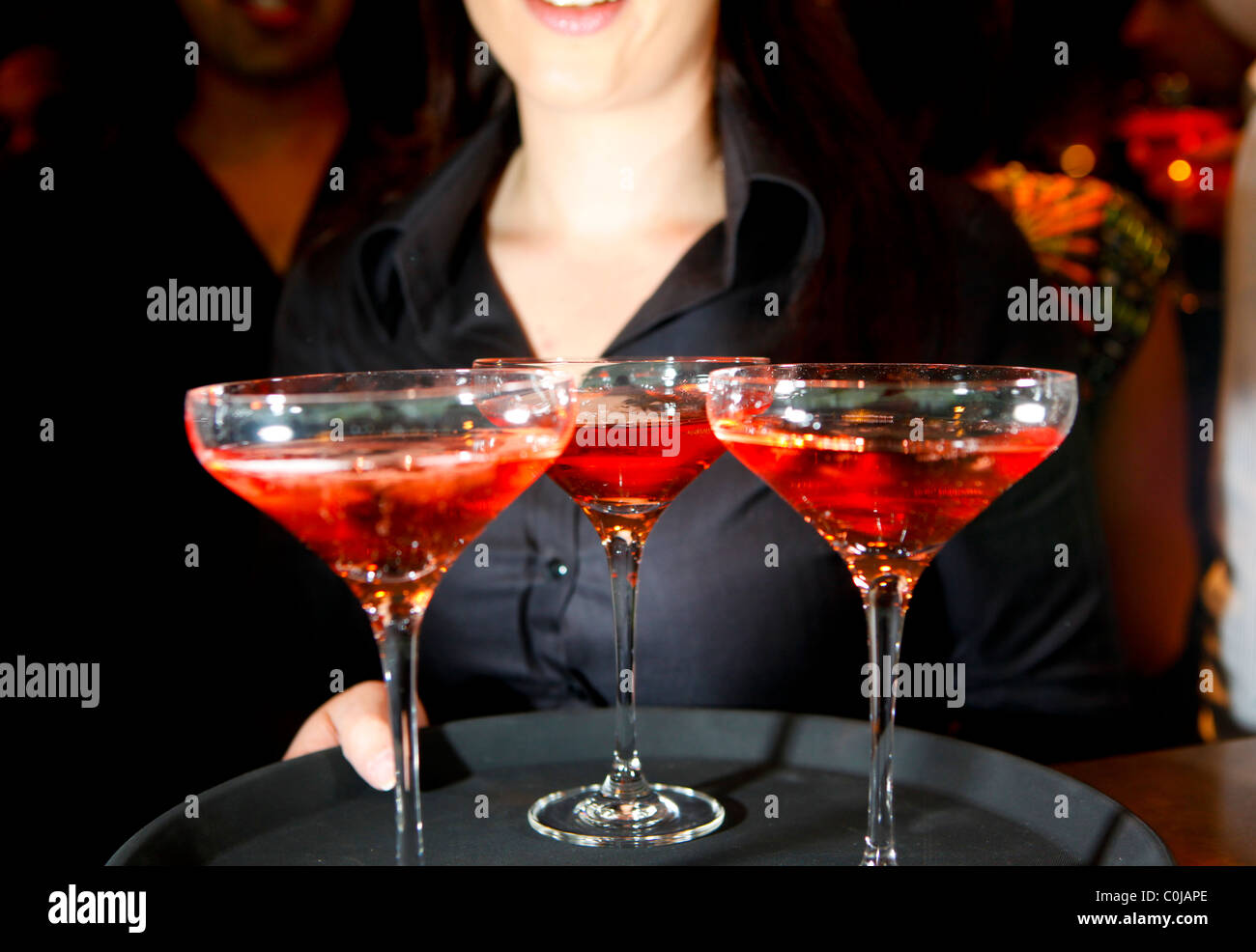 Una cameriera tenendo un vassoio di rosa bicchieri di champagne in un bar Foto Stock