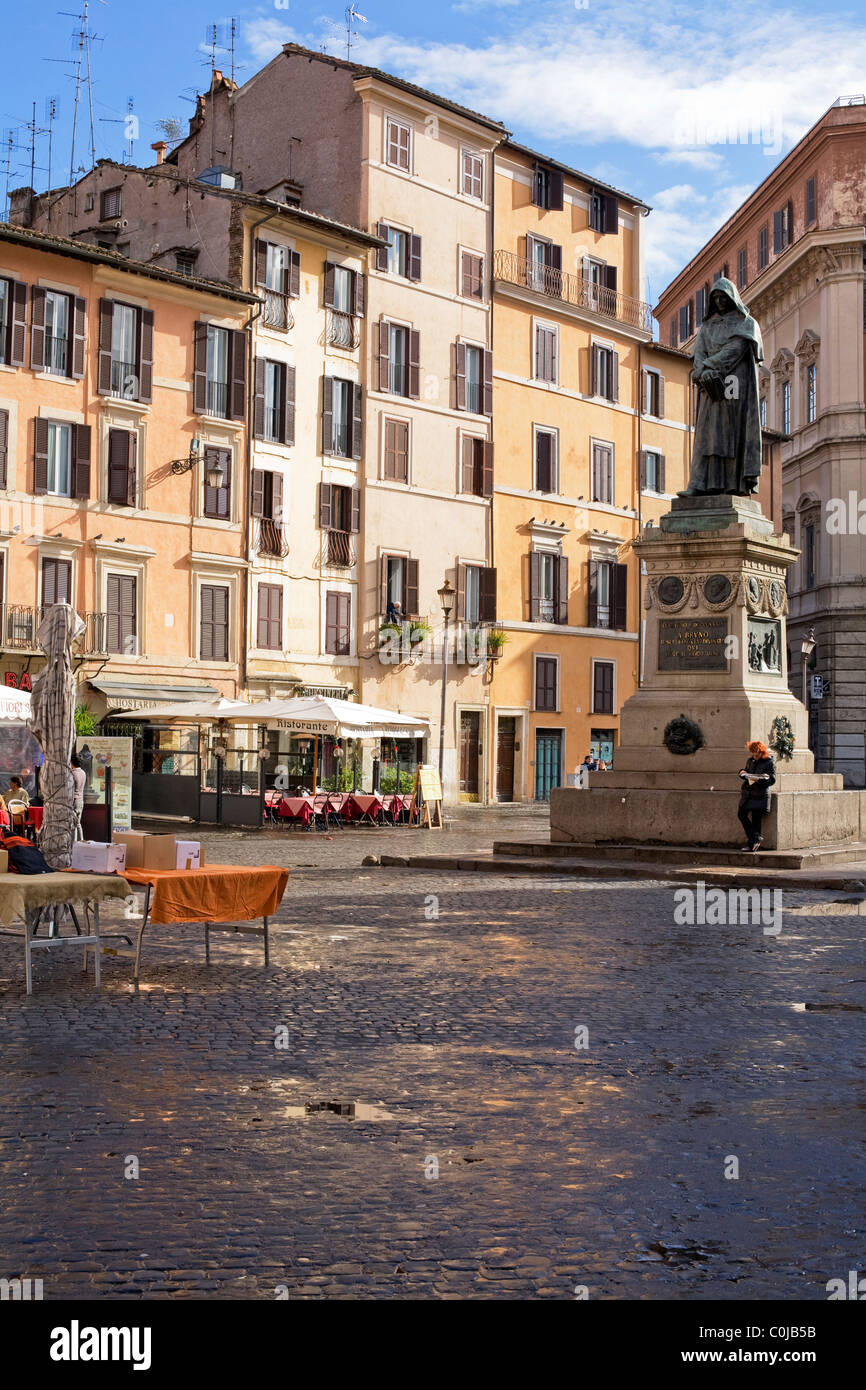 Donna leggendo un giornale ai piedi della statua di Giordano Bruno in Campo dei Fiori, Roma, Italia Foto Stock